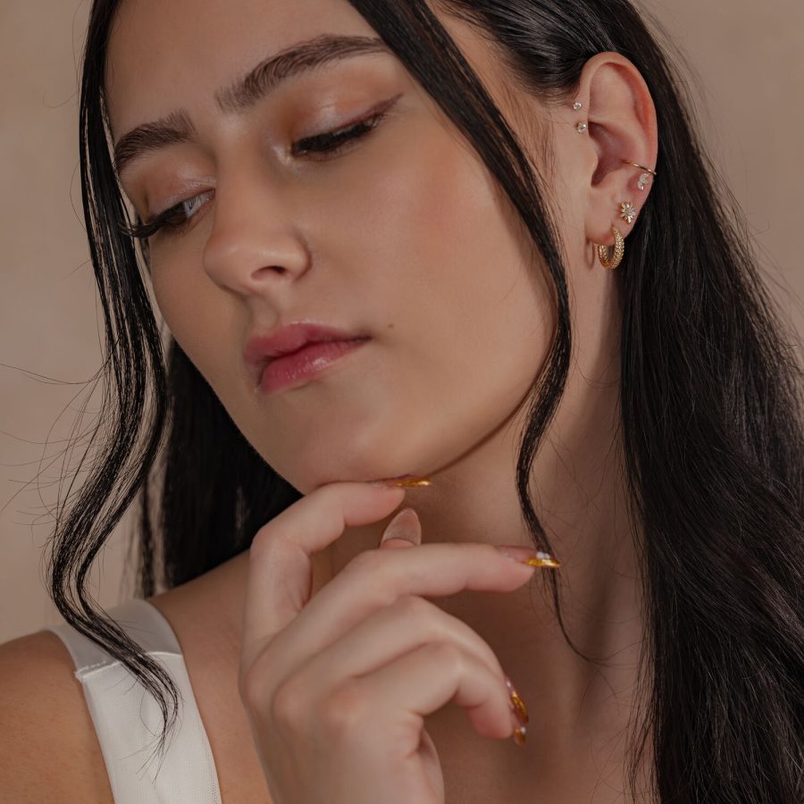 Frau mit 14K Gold Crystal Hinged Ring und weiteren Ohrringen im Ohr