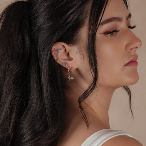Frau mit 18K Gold Hinged Ring im Ohr, seitliches Profil, dunkles Haar