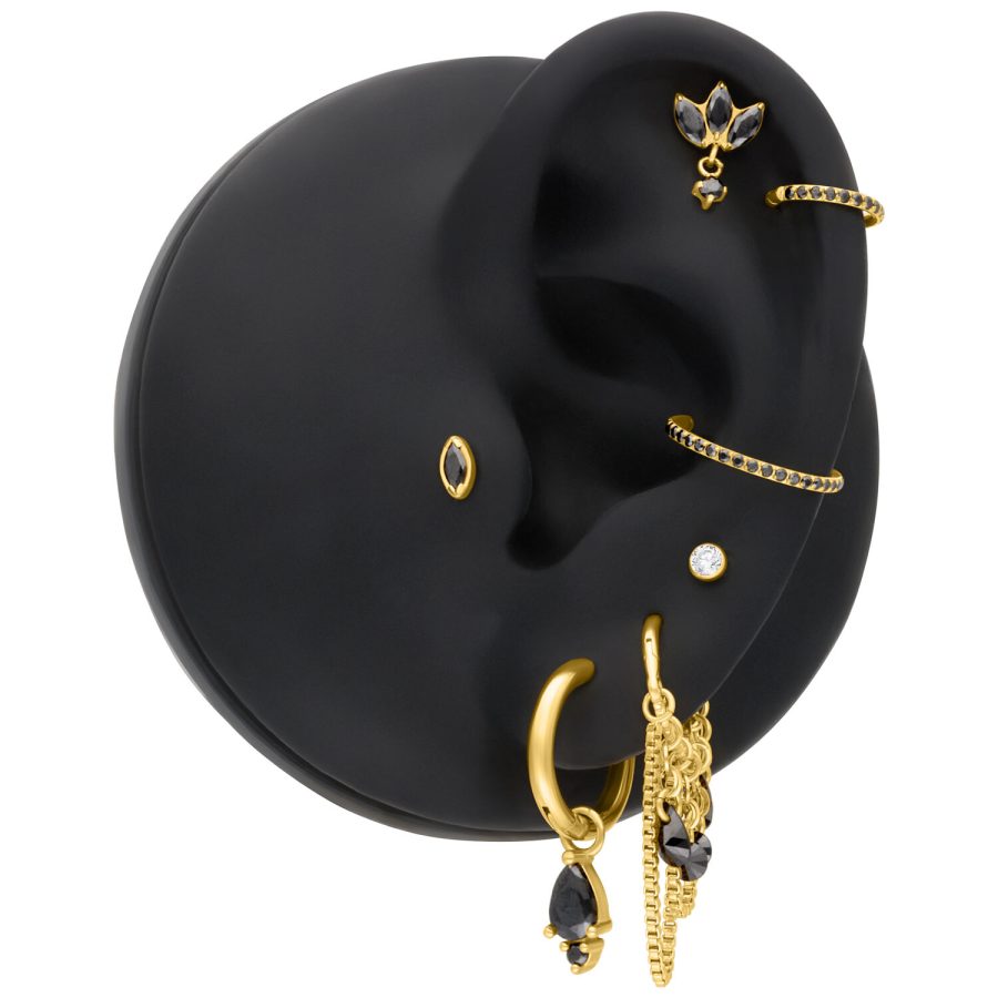 Goldener Piercing-Aufsatz mit diamantschwarzem Kristall auf schwarzem Ohr-Modell