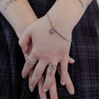 Silbernes Armband mit Herzanhänger an Handgelenk, getragen von einer Person.