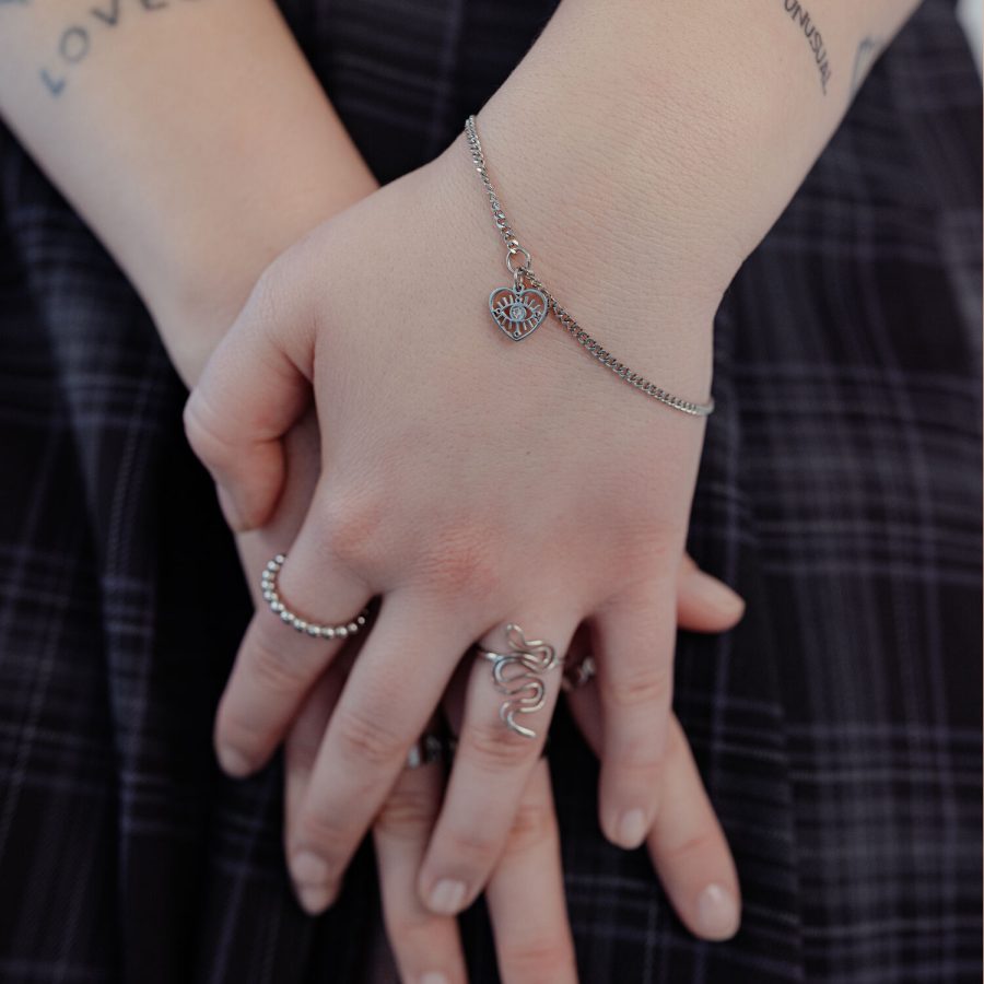Silbernes Armband mit Herzanhänger an Handgelenk, getragen von einer Person.