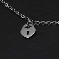Silbernes Armband mit Herzschloss-Anhänger auf schwarzem Hintergrund