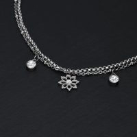 Silbernes Armband auf schwarzem Hintergrund mit floralen Anhängern und Kristallen