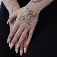 Zwei Hände mit Little Nazar Armband auf schwarzem Hintergrund