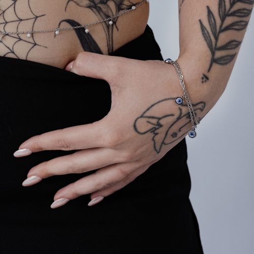 Silbernes Armband mit Nazar-Anhänger am Handgelenk, tätowierte Hand
