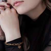 Frau mit goldfarbenem Herz Armband auf schwarzem Hintergrund