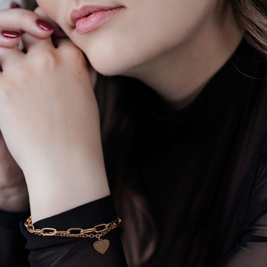 Frau mit goldfarbenem Herz Armband auf schwarzem Hintergrund