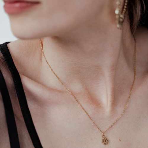 Dame mit goldener Little Sunflower Kette, filigran und elegant, auf hellem Hintergrund