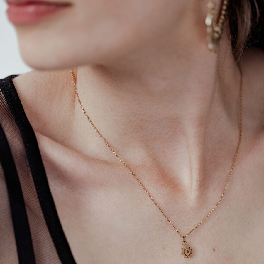 Dame mit goldener Little Sunflower Kette, filigran und elegant, auf hellem Hintergrund