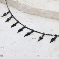 Schwarzes Snake Armband mit verstellbarem Verschluss auf hellem Stein