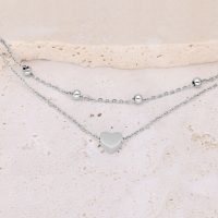Silbernes doppelreihiges Armband mit Herz und Kugeln auf hellem Hintergrund