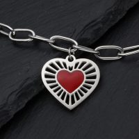 Silberfarbenes Armband mit rotem Herzanhänger auf dunklem Hintergrund