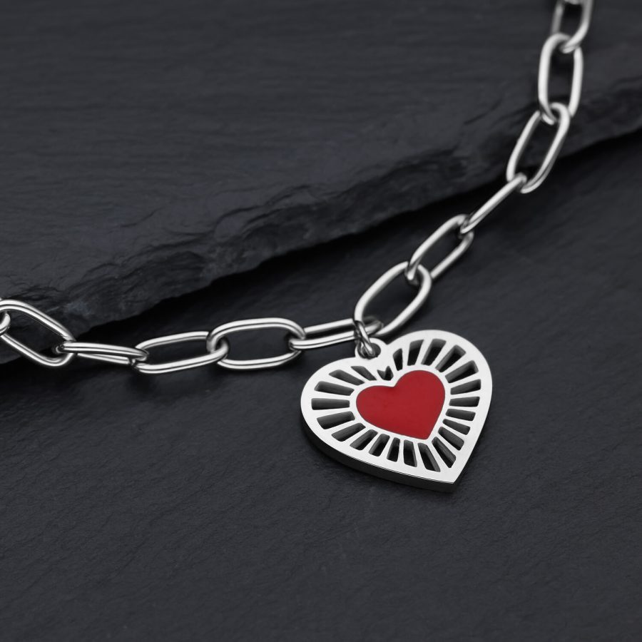 Silberfarbenes Armband aus Chirurgenstahl mit rotem Herzanhänger auf dunklem Hintergrund