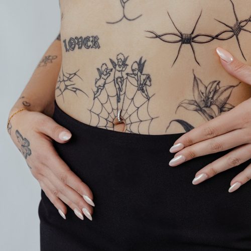 Bauchnabel mit schwarzem Kristall Clicker und Tattoos auf heller Haut