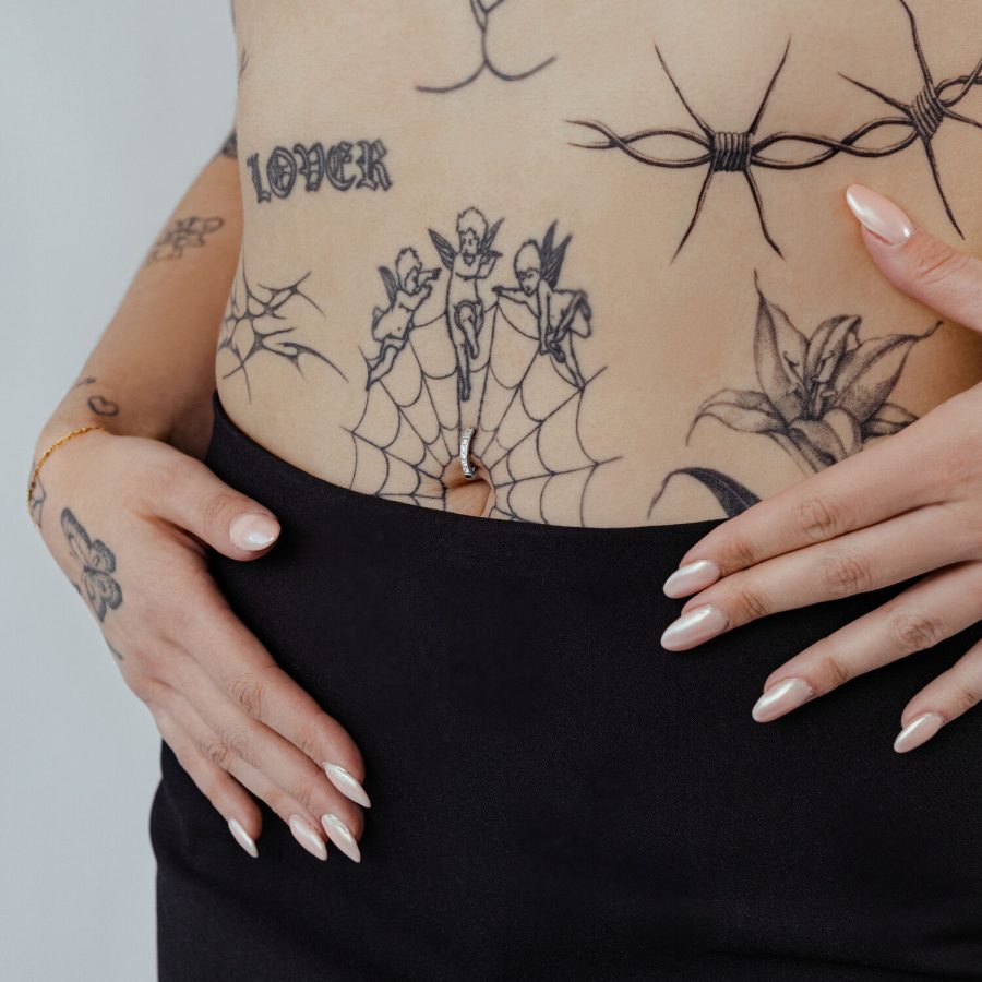 Bauchnabel mit schwarzem Kristall Clicker und Tattoos auf heller Haut