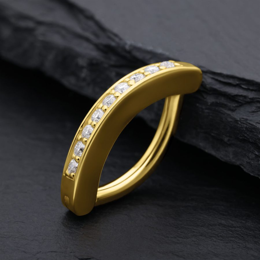 Goldener Bauchnabel Clicker mit Moissanit Kristallen auf schwarzem Hintergrund