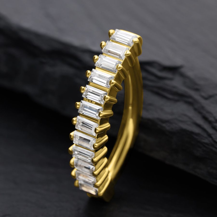 Goldener Bauchnabel Clicker mit Moissanit Baguette Kristallen auf dunklem Hintergrund