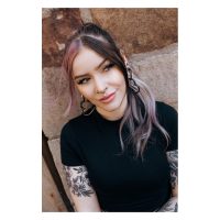 Frau mit schwarzem Concave Septum Clicker und langem Haar vor Steinwand