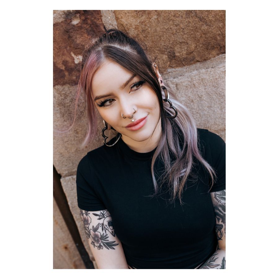 Frau mit schwarzem Concave Septum Clicker und langem Haar vor Steinwand