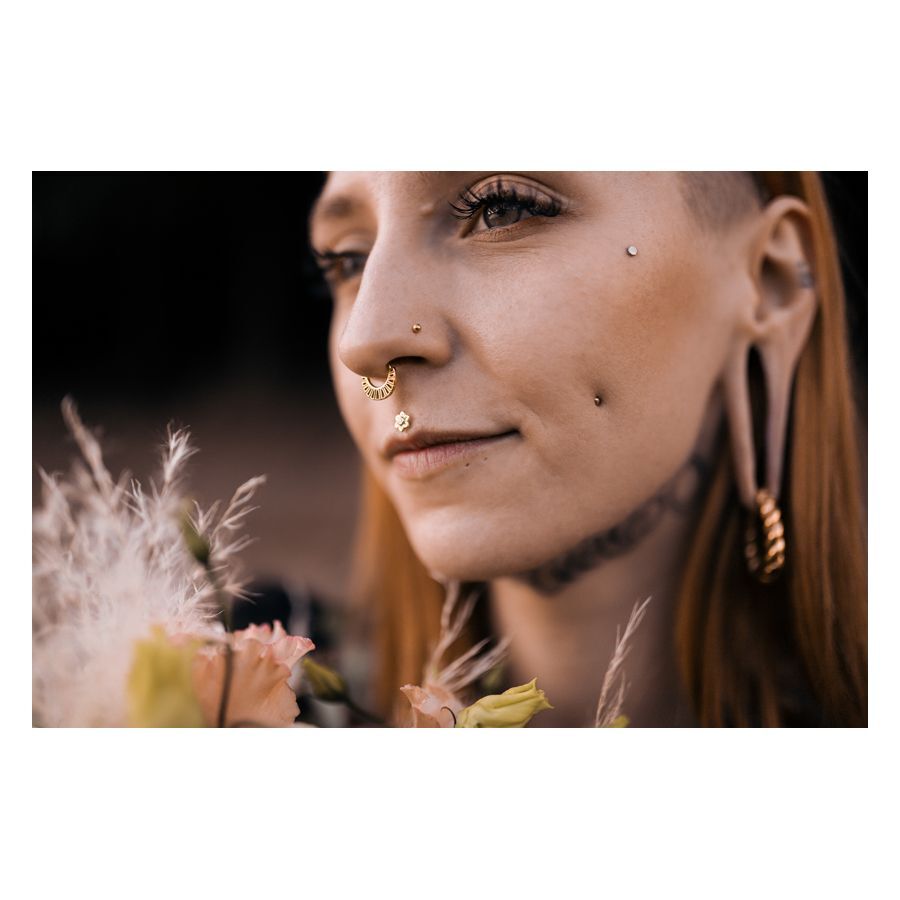 Frau mit Flower Push-Fit Labret im Ohr, umgeben von Blumen, im Freien