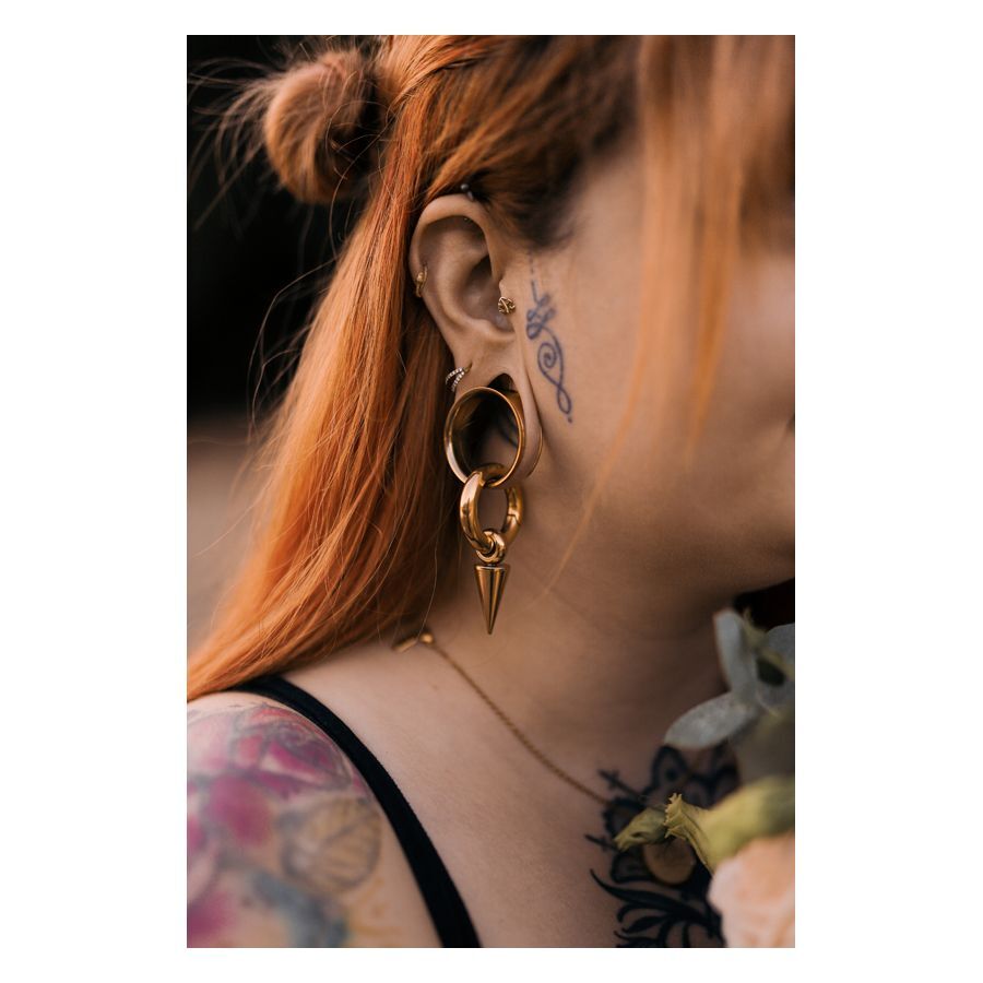 Frau mit rotem Haar trägt goldenen Monstera Push-Fit Labret im Ohr, Tattoos sichtbar