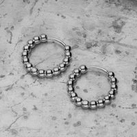 Zwei silberne Bubble Hoops Ohrringe aus Edelstahl auf grauem Betonhintergrund