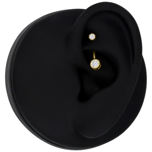 Goldenes Piercing mit klarem Kristall an schwarzem Ohrmodell