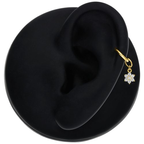 Goldener Blumenanhänger mit Moissanit an einem Ohr auf schwarzem Hintergrund