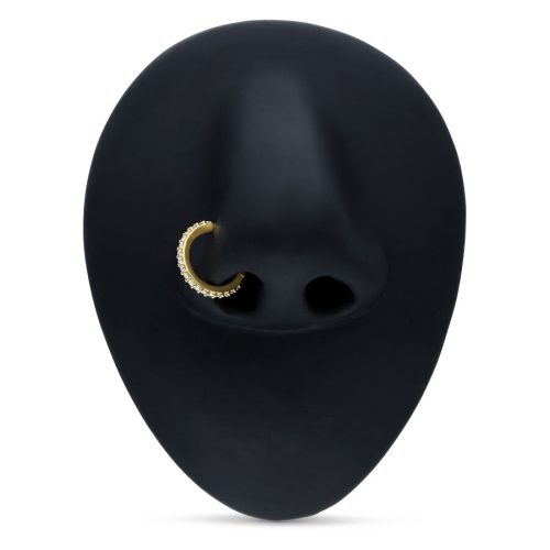 Goldener Piercingring mit Kristallen auf schwarzem Hintergrund