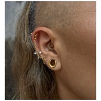 Piercing im Ohr mit 14K Gold Clicker und klaren Kristallen, seitlich fotografiert
