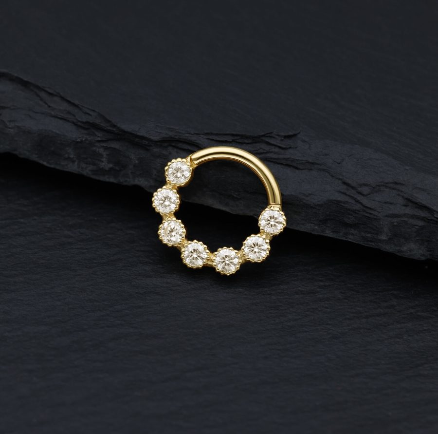 Goldener Piercingring mit funkelnden Moissanit Steinen auf schwarzem Hintergrund