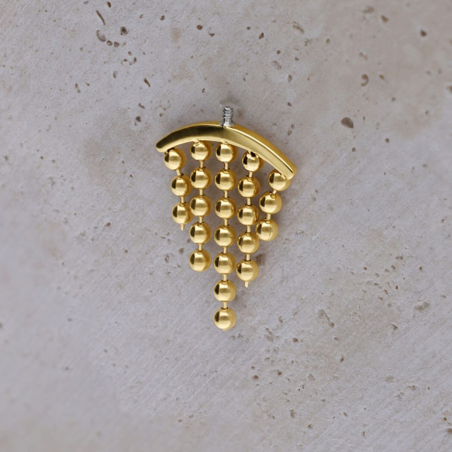 Goldfarbener Helix-Piercing-Aufsatz mit hängenden Kugeln auf hellem Hintergrund