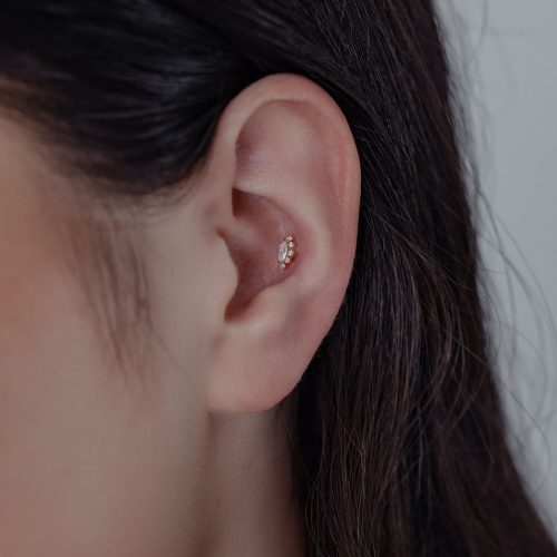Nahaufnahme eines Ohres mit 14K Gold Moissanite Aufsatz auf neutralem Hintergrund