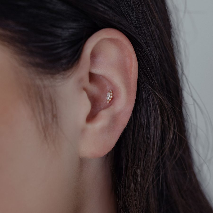 Nahaufnahme eines Ohres mit 14K Gold Moissanite Aufsatz auf neutralem Hintergrund