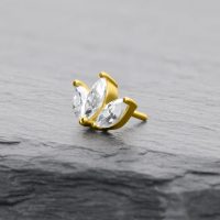 Goldener Lotusblütenaufsatz mit zwei klaren Zirkonia auf grauem Stein