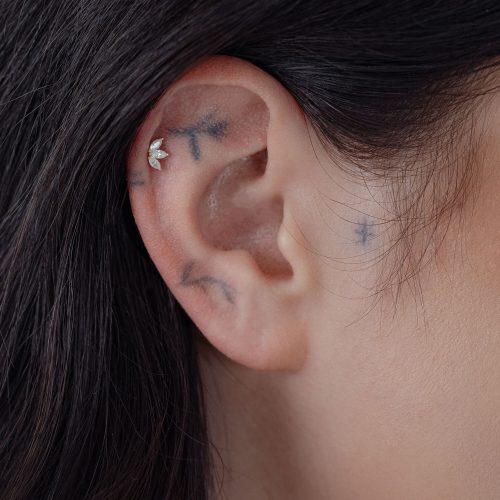 14K Gold Lotusblüten-Aufsatz am Ohr einer Person mit dunklem Haar