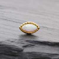 Ovaler synthetischer Opal in goldener Fassung auf grauem Hintergrund