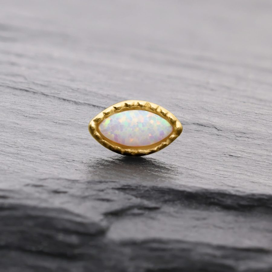 Ovaler synthetischer Opal in goldener Fassung auf grauem Hintergrund