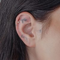 Goldener Aufsatz mit synthetischem Opal in einem Ohrpiercing.