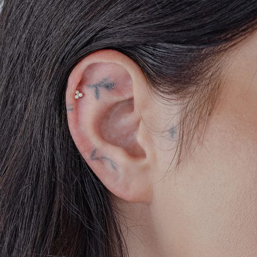 Goldener Aufsatz mit synthetischem Opal in einem Ohrpiercing.