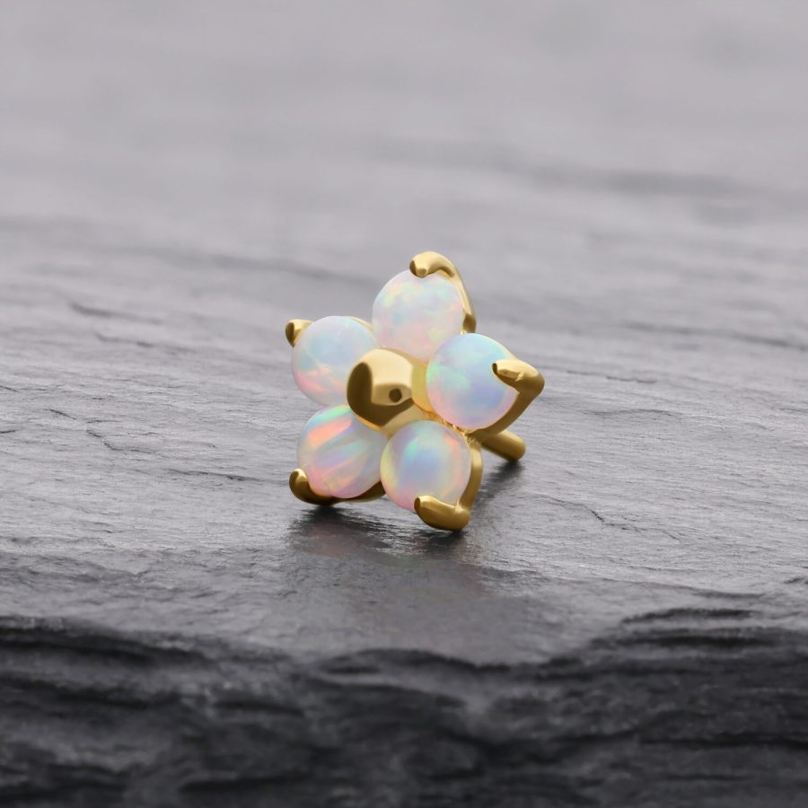 Goldener Blume-Aufsatz mit synthetischem Opal auf grauem Hintergrund
