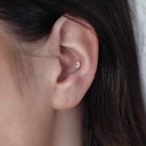 Nahaufnahme eines Ohres mit einem 14K Gold Blume Opal Aufsatz