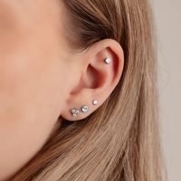 Nahaufnahme eines Ohrs mit silbernem Disc für Triple Piercing in 4,0 mm Größe auf hellem Hintergrund