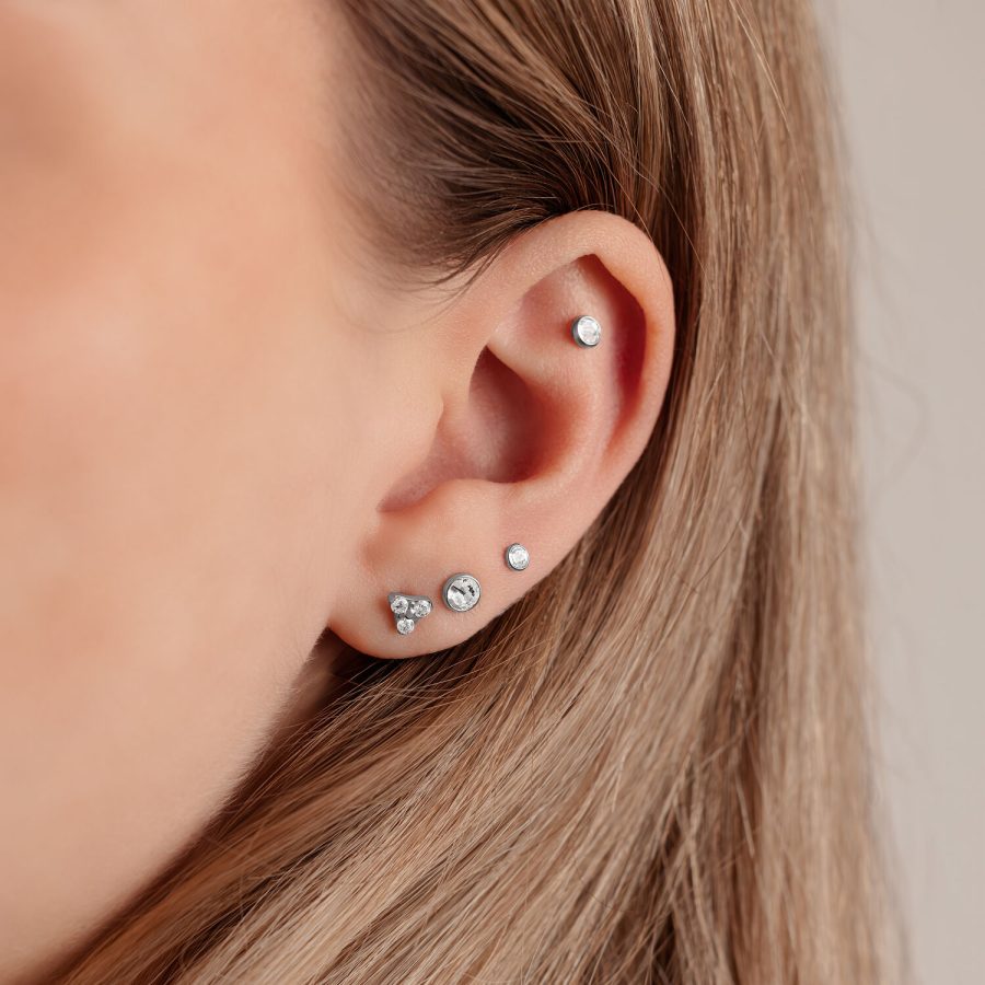 Nahaufnahme eines Ohrs mit silbernem Disc für Triple Piercing in 4,0 mm Größe auf hellem Hintergrund