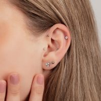 Nahaufnahme eines Ohrs mit mehreren Titan-Piercings in Schwarz und Silber