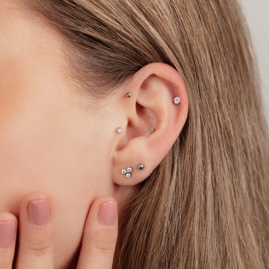 Nahaufnahme eines Ohrs mit mehreren Titan-Piercings in Schwarz und Silber