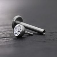 Silberner Labret-Aufsatz mit klarer Kristallkugel auf grauem Hintergrund