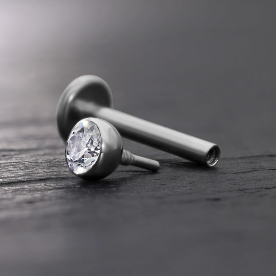 Silberner Labret-Aufsatz mit klarer Kristallkugel auf grauem Hintergrund