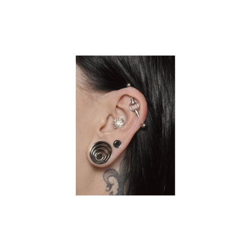 Nahaufnahme eines Ohres mit silbernem Industrial Piercing und weiteren Ohrschmuckstücken