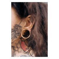 Roségoldenes Bananabell Piercing im Ohr mit Tattoo im Hintergrund